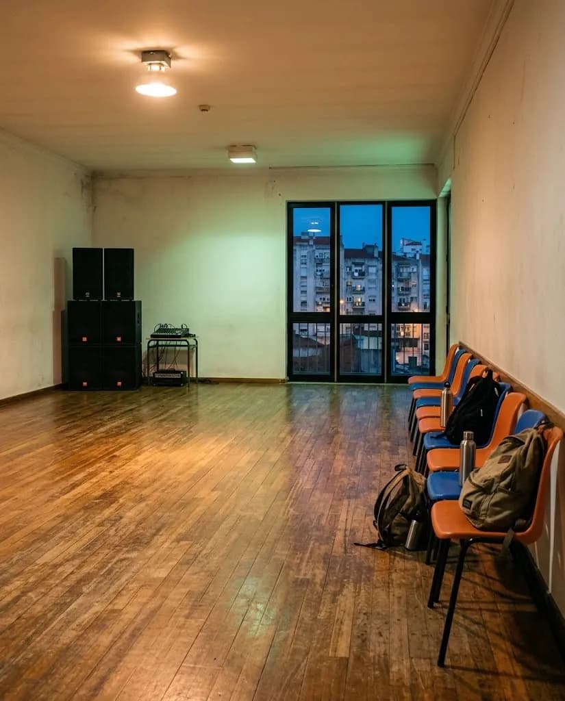 Um salão comunitário transformado em estúdio de dança ao fim do dia, com colunas empilhadas ao canto
